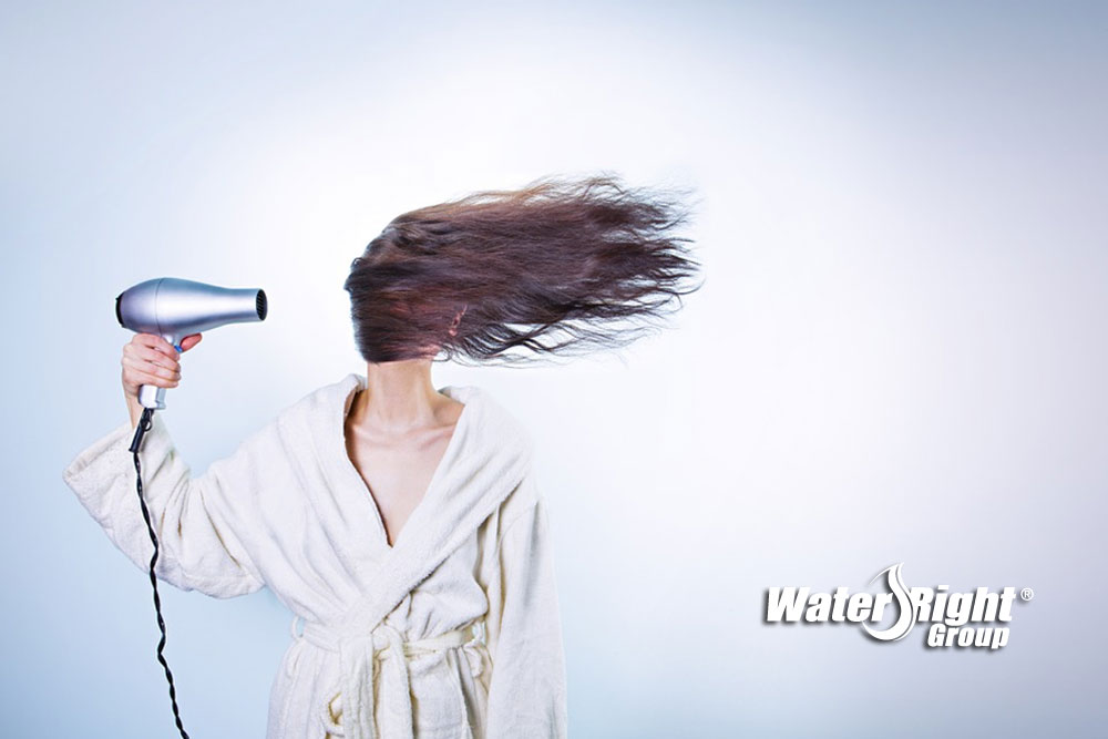 woman blowdrying frizzy hair from hard water