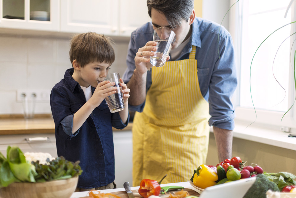 father and son drinking clean water and preparing healthy meal